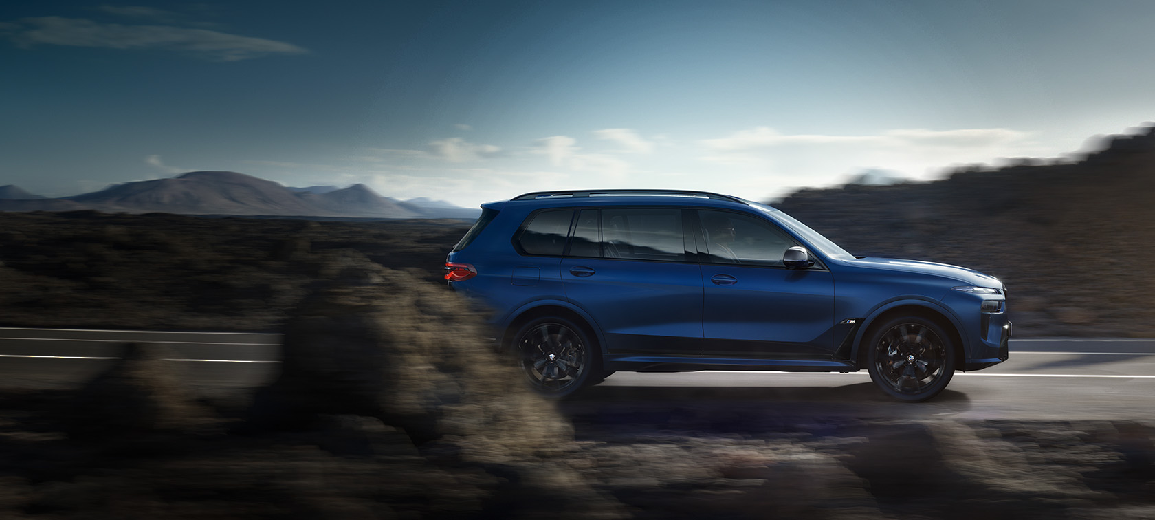 BMW X7 M60i xDrive G07 LCI Frozen Marina Bay Blue Sett fra siden kjørende på veien